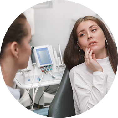 Woman holding her cheek in pain while talking to a dentist