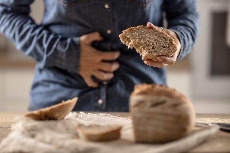 Someone clutching their stomach while holding a piece of bread